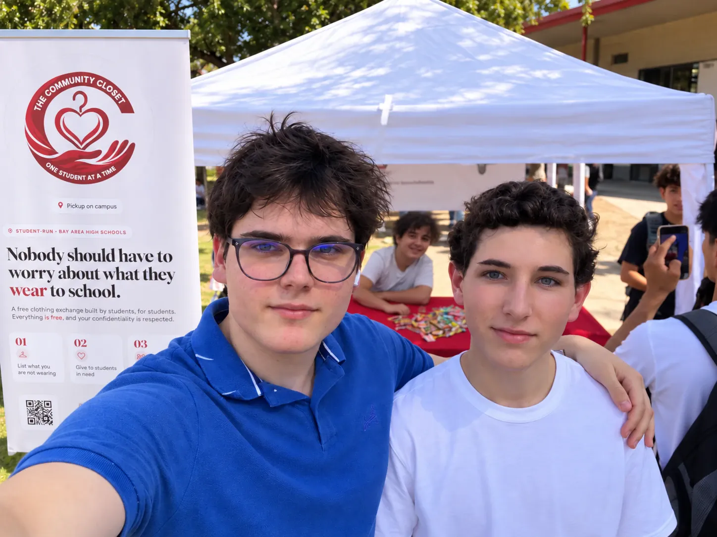 Alex Messerlian and Balthazar Sauquet at The Community Closet booth at Club Rush, with Shalev Amirav Drory at the table behind them.